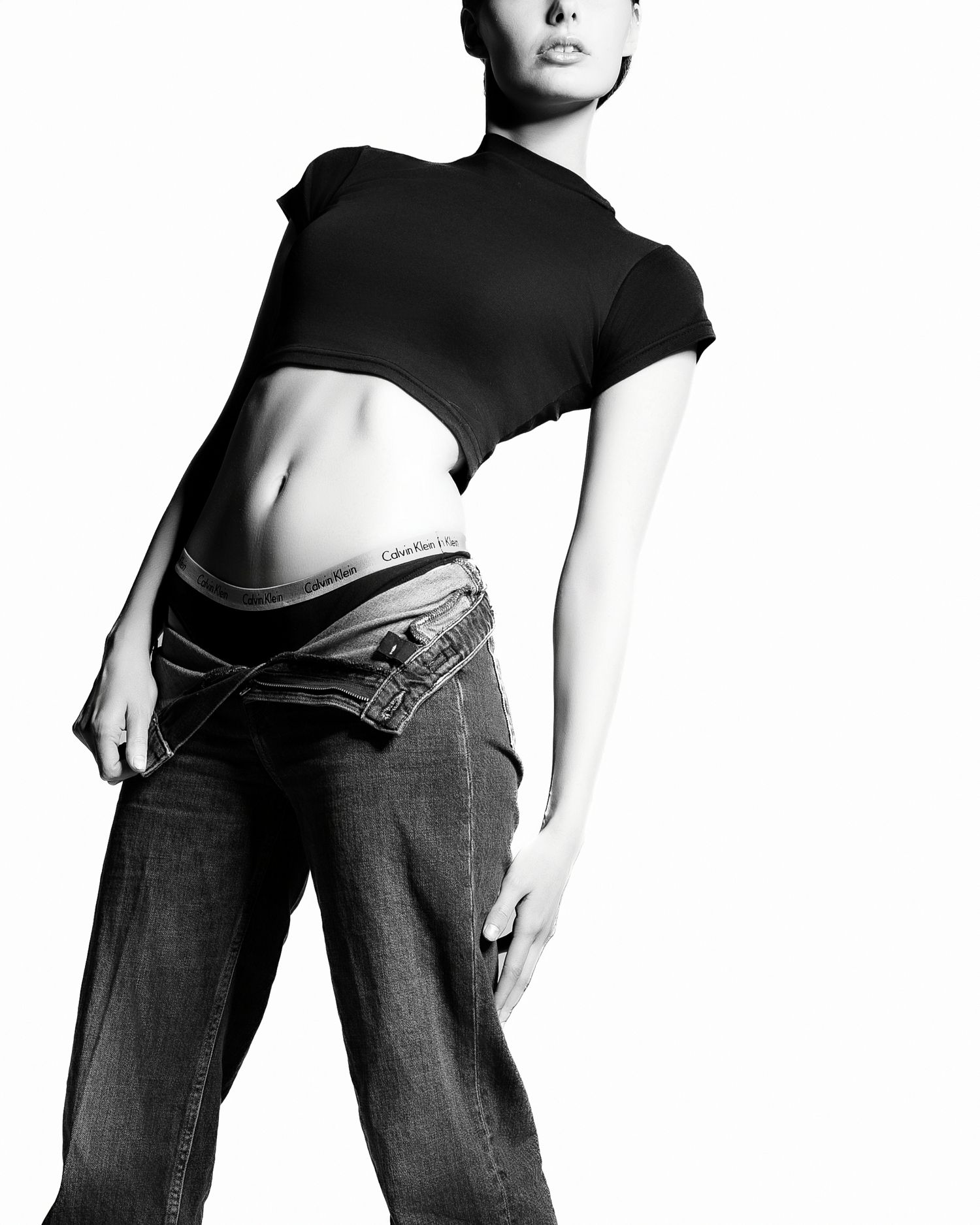 Black and white fashion photo showing a cropped black top and jeans in minimalist style against white background.