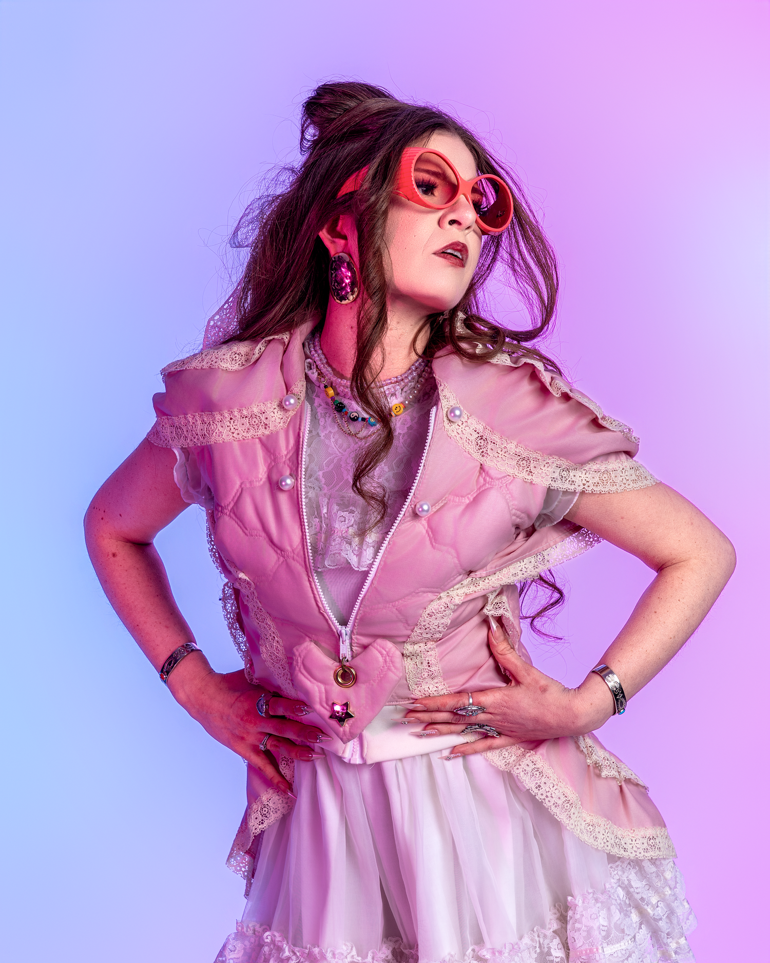 Model wearing vintage-inspired pink lace dress poses dramatically in studio lighting.