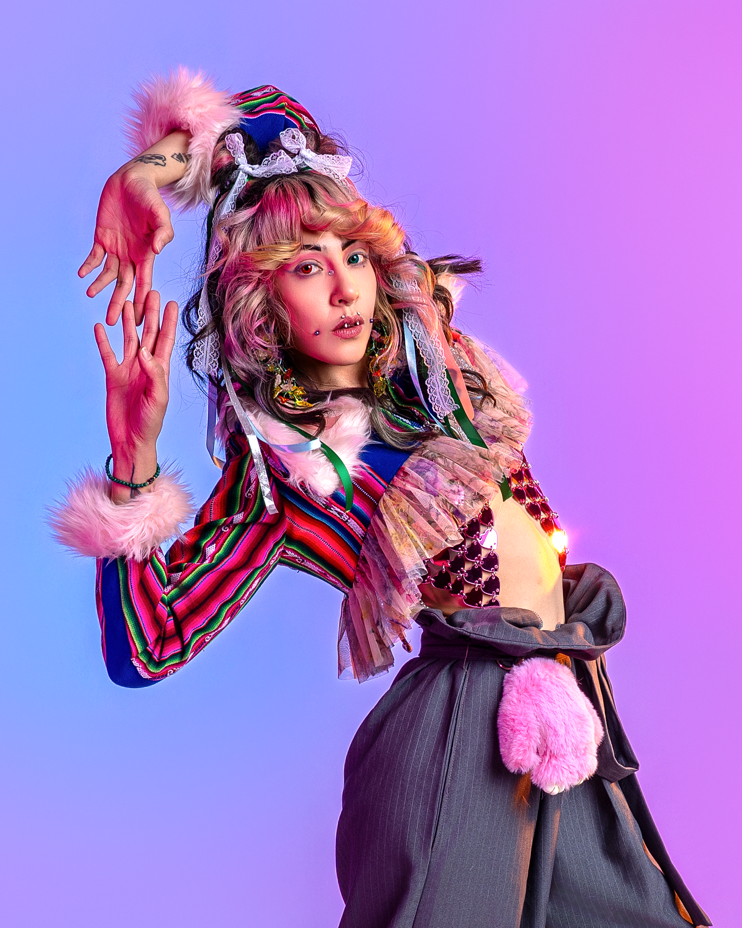 Fashion model poses dramatically in dark overalls with colorful accessories against gradient purple background.