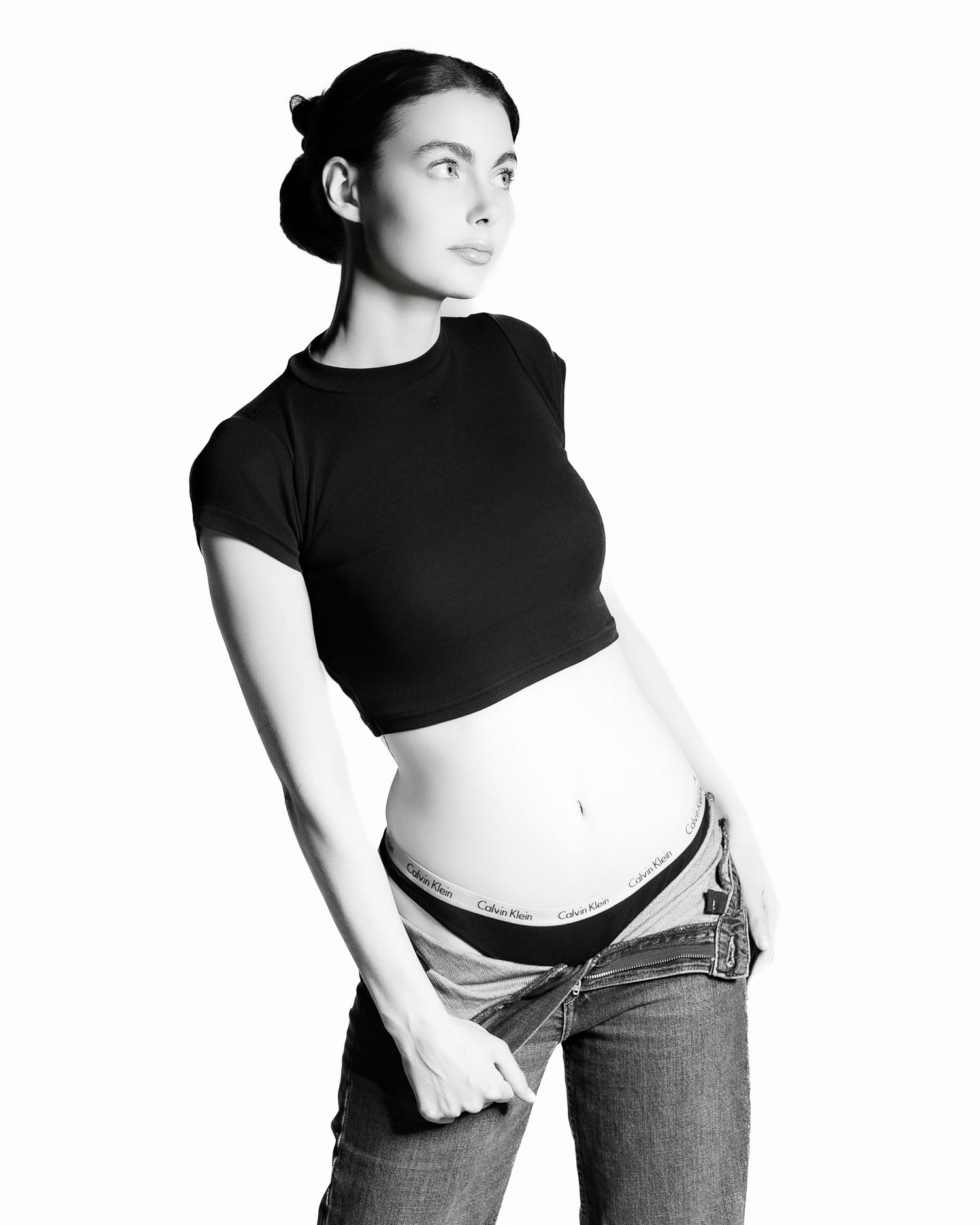 Black and white fashion photo series showing three cropped poses in black top and jeans against white background.