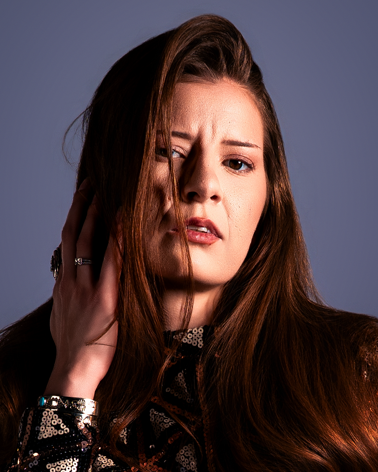 A dramatic fashion portrait series with moody lighting showcases a model with flowing hair against a dark background.