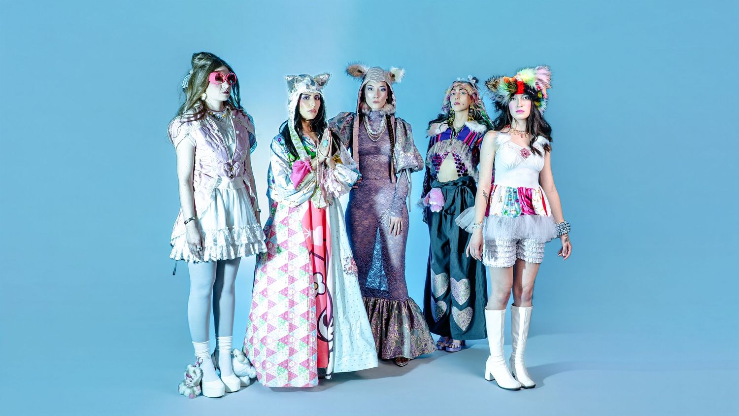 Group of models in colorful retro outfits posed against blue background.