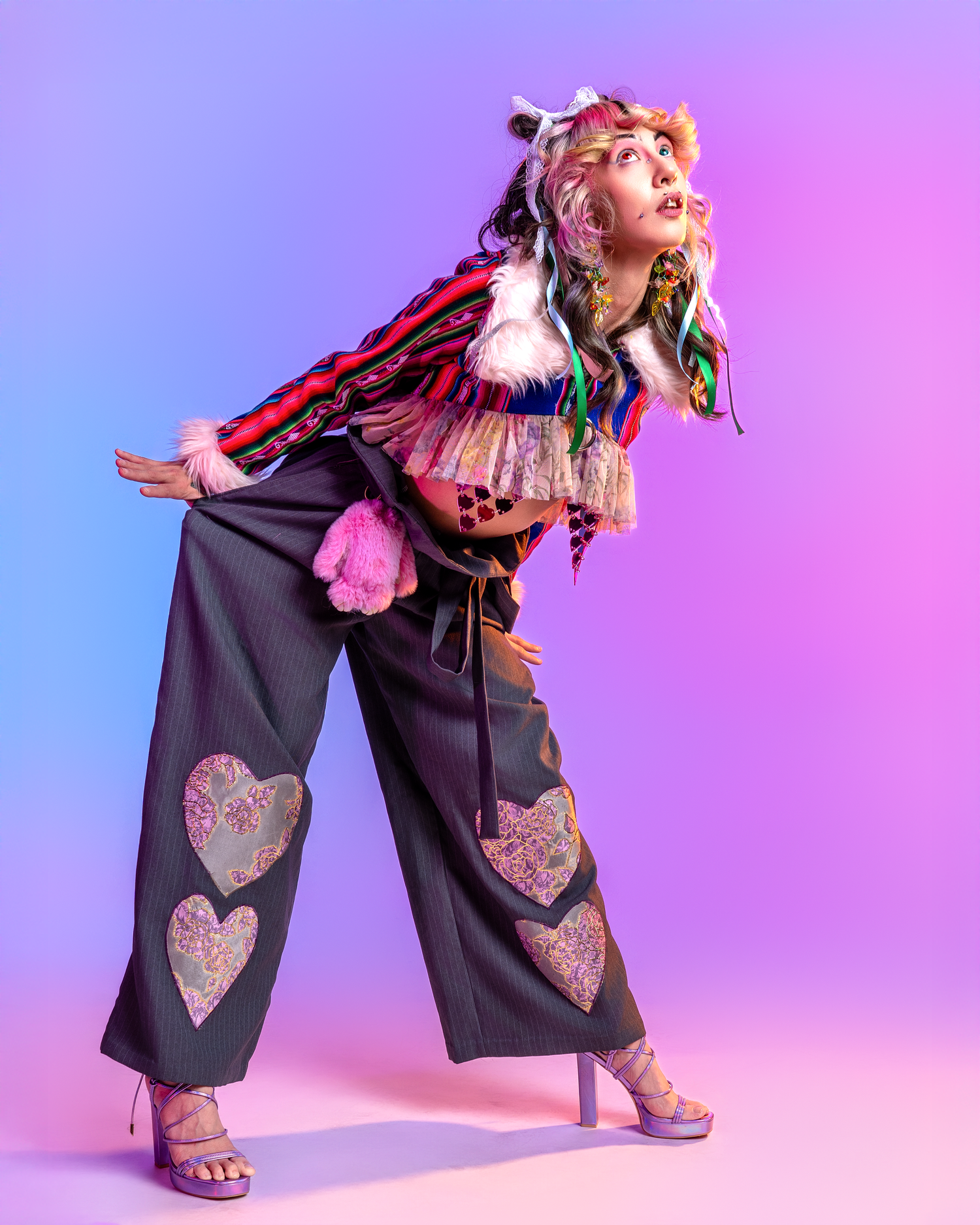 Wide-leg jumpsuit with heart details shown in dynamic pose against colorful studio background.