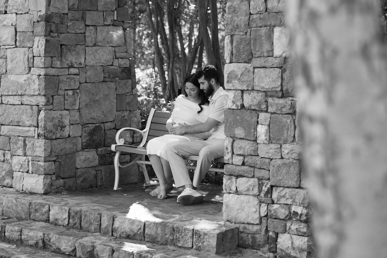 couple sitting and relaxing on stone architecture in a black and white photograph.