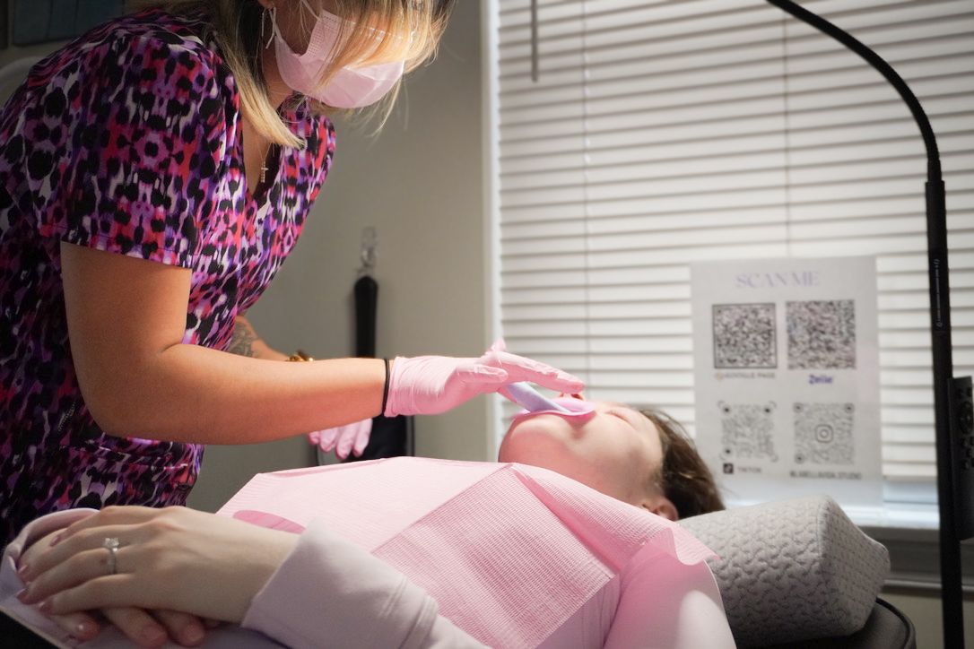 A technician working on a client's teeth whitening in a salon setting.