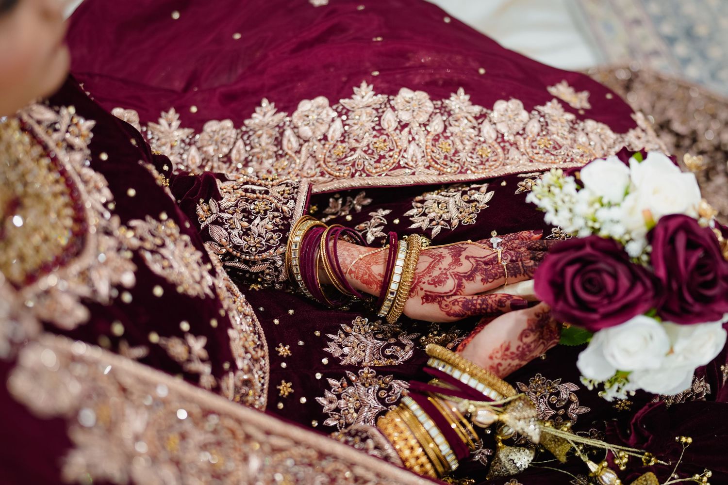 Wedding details featuring burgundy fabric, roses, and gold accents.