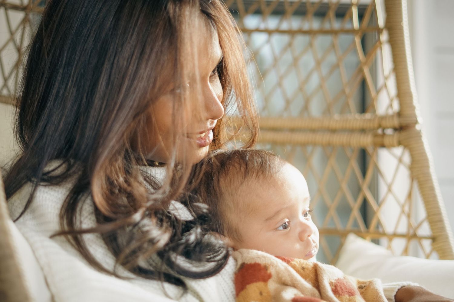 photography of mother in white sweater tenderly holds and gazes at infant baby in peaceful moment.