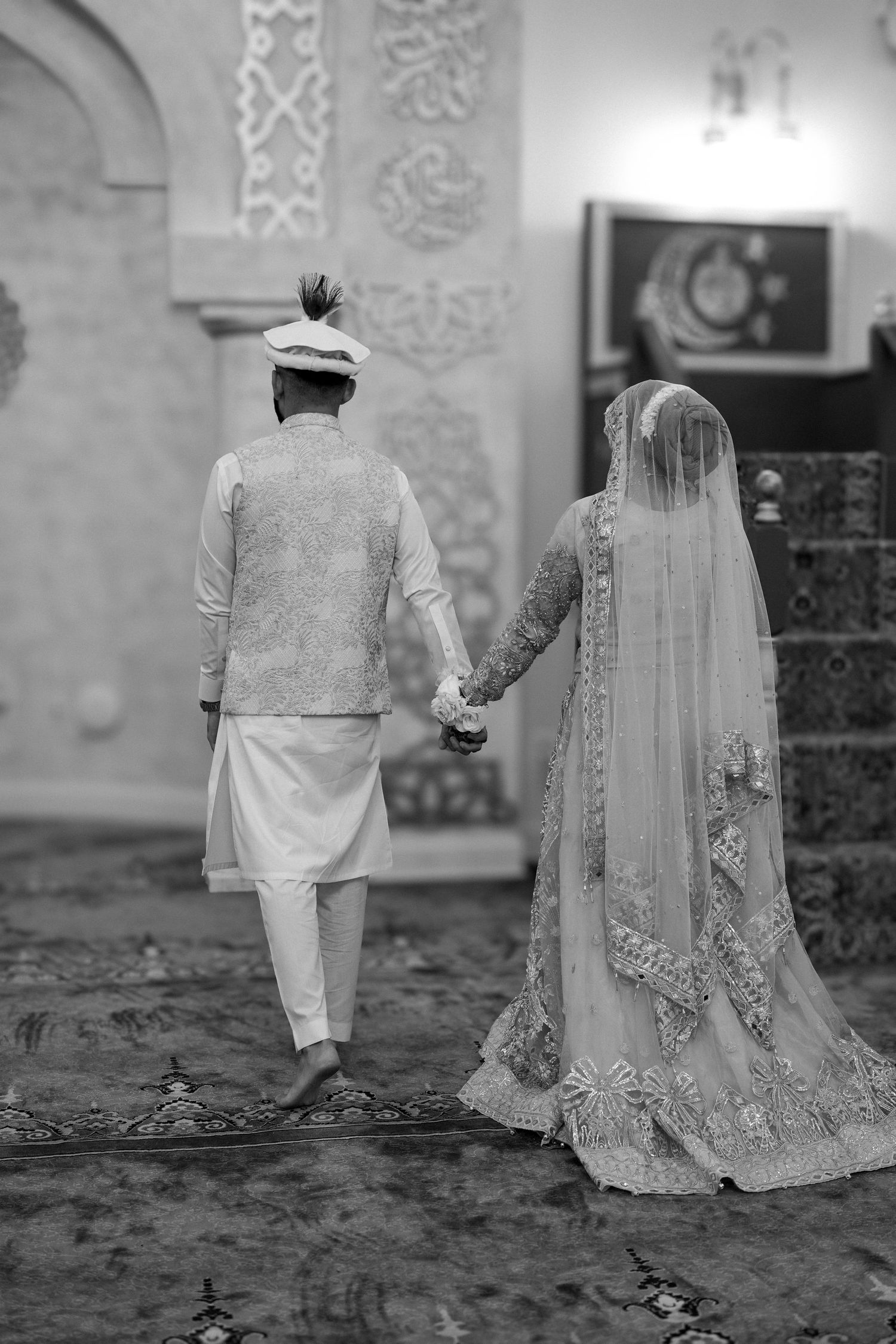 Black and white wedding photos showing a couple in traditional South Asian attire walking together.