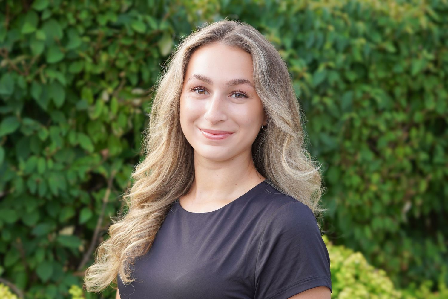 Outdoor portrait series featuring girl in a black top against lush green foliage.