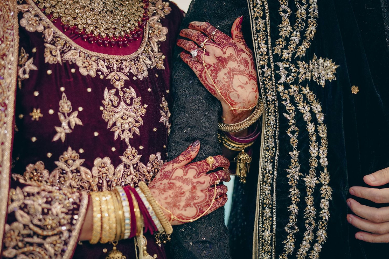 Traditional south asian wedding attire with detailed embroidery and rich burgundy fabrics.
