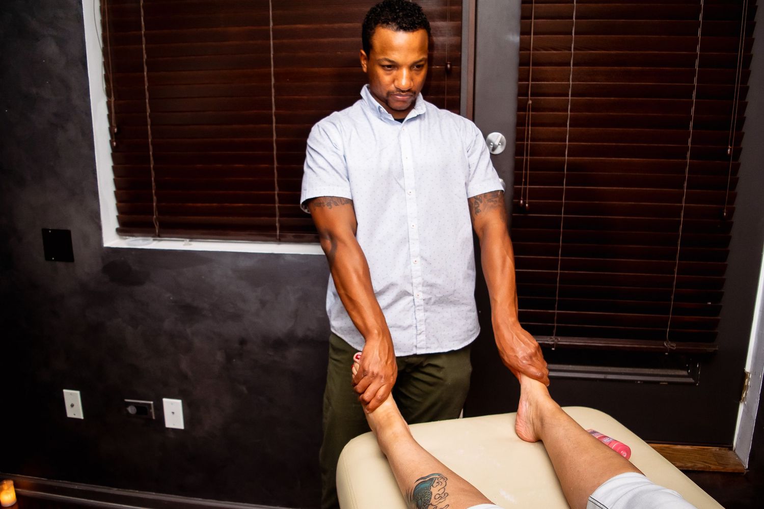Professional massage therapist performing foot and ankle massage on client.