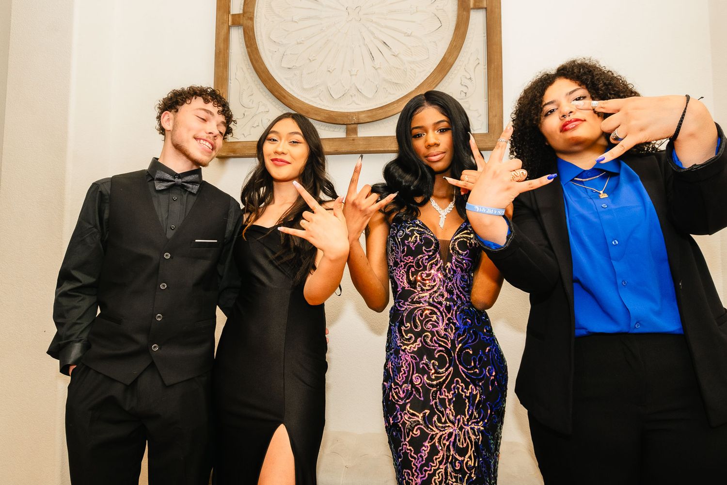 Four teens in formal attire posing together at prom night.