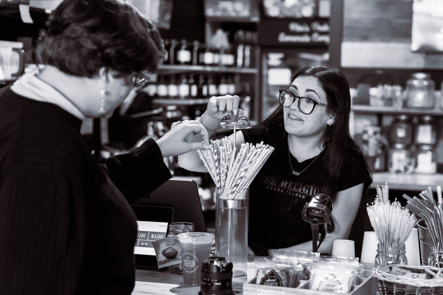 Black and white photo of a female bartender serving a customer at a bar.