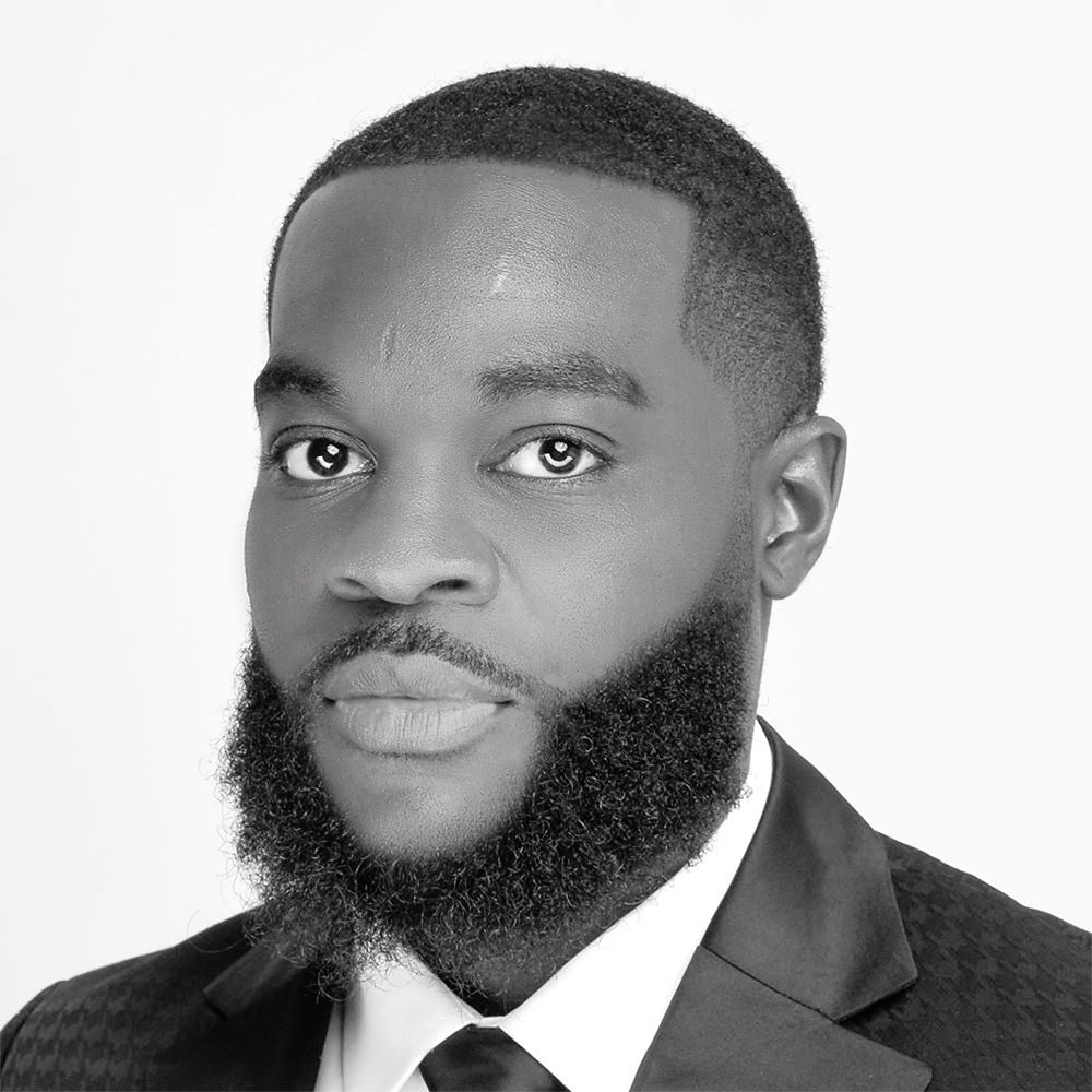 Professional black and white headshot portrait of a bearded man in a suit.