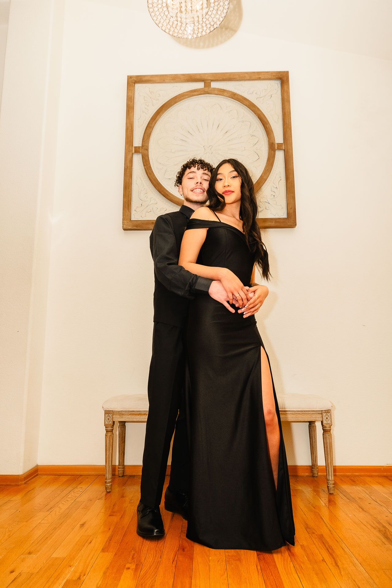 Couple embracing in elegant black formal wear at prom.