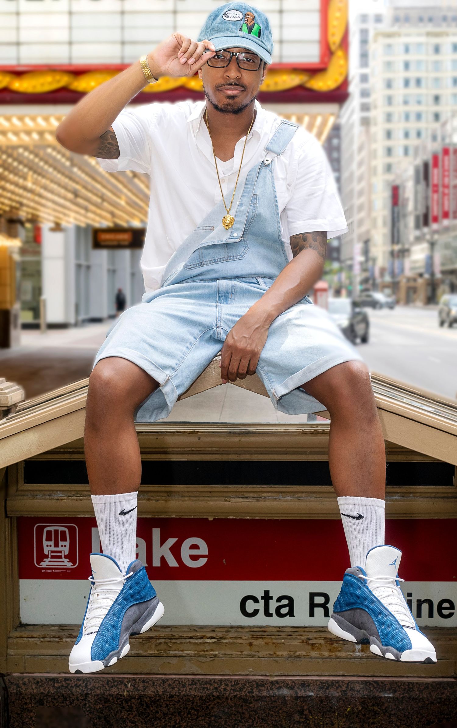 Man in denim overalls and Jordan 13s sits on CTA Lake station sign in Chicago.