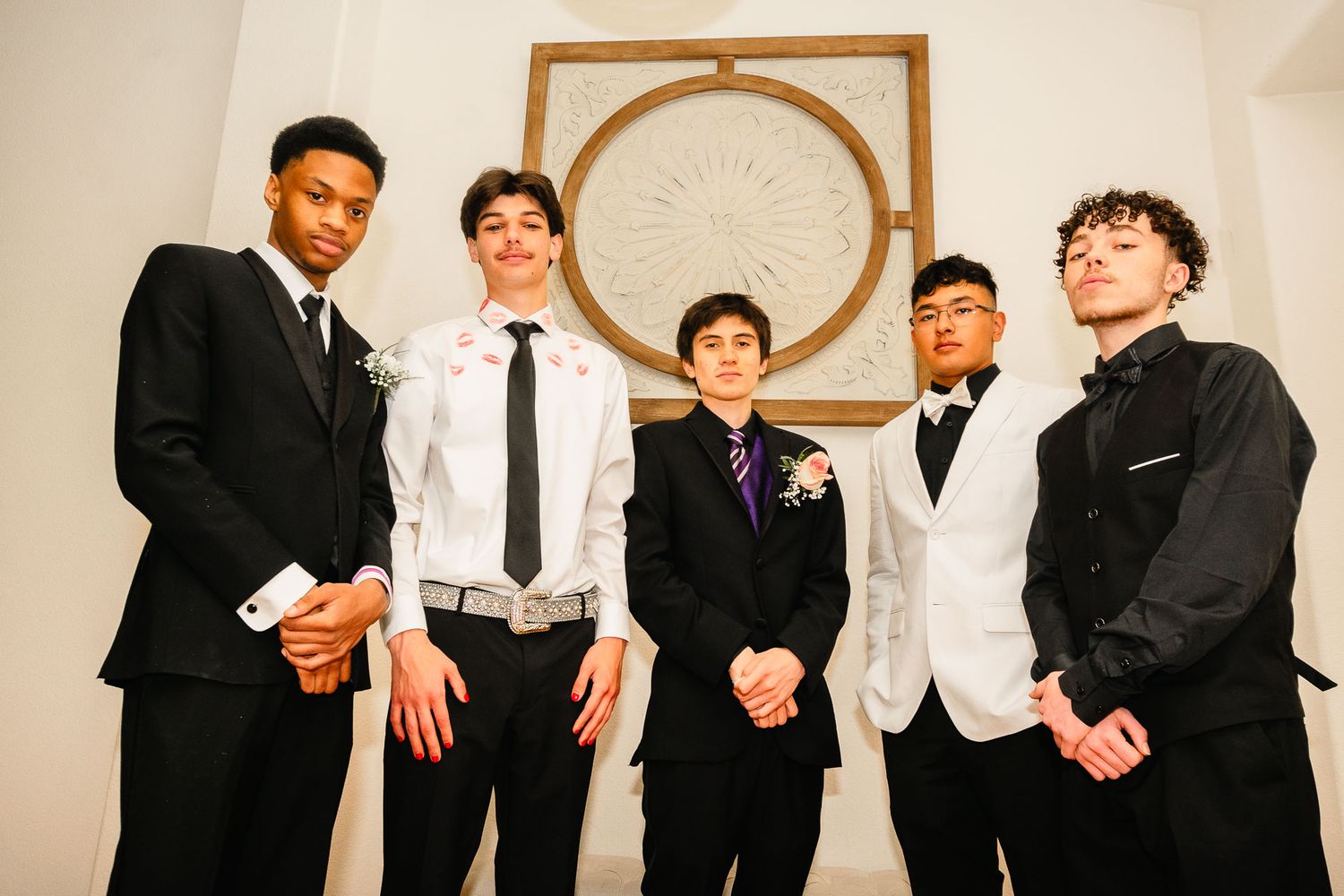 Five teenage boys in formal attire posing for prom picture.