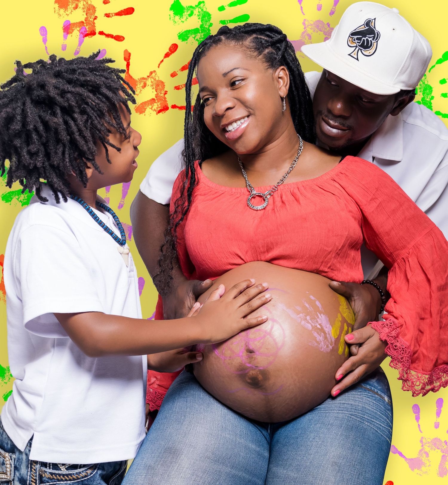 Pregnant woman with painted belly smiling with partner and child in colorful maternity photo.