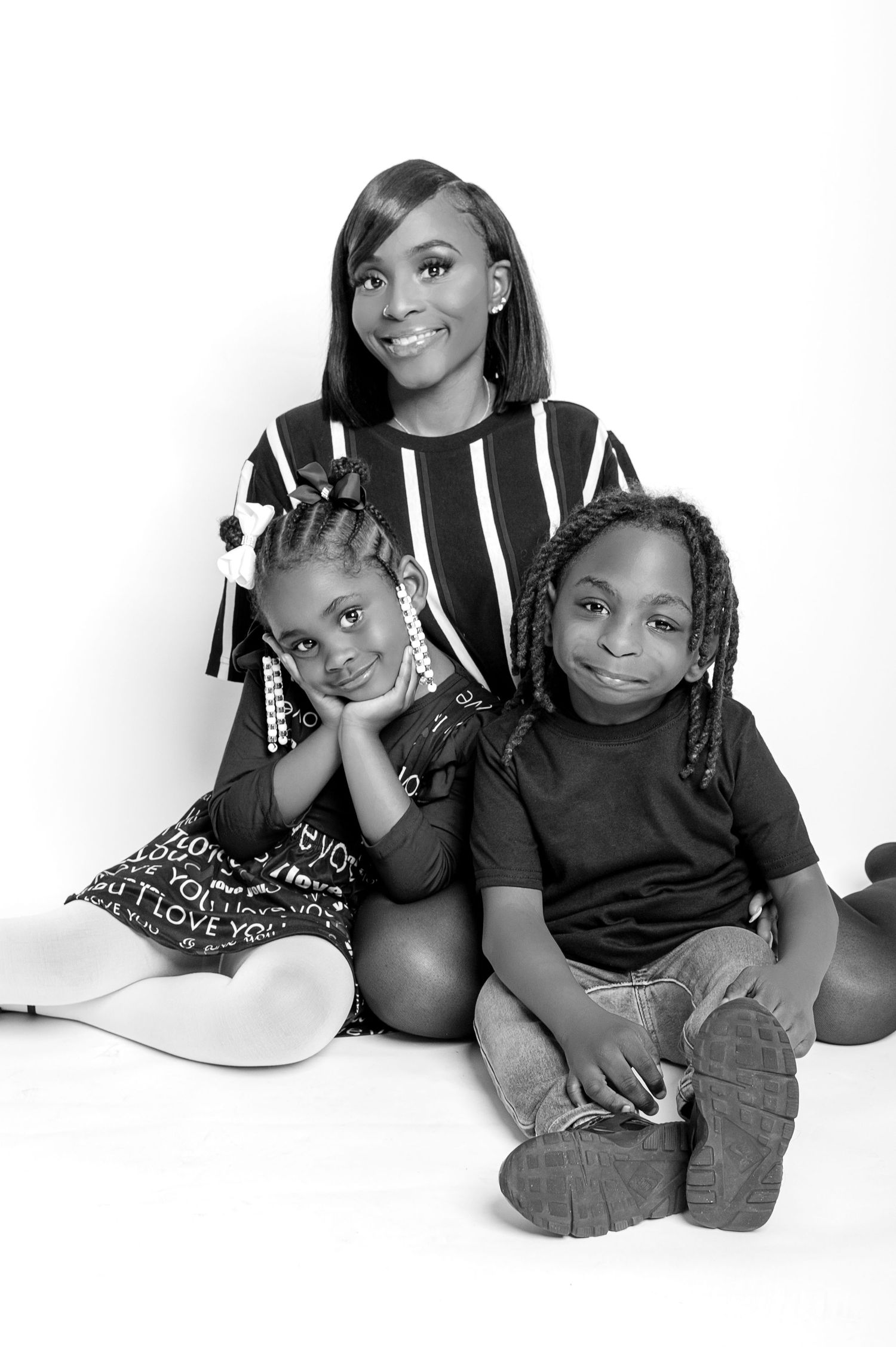 Black and white family portrait of a mother and two children posing together in a studio.