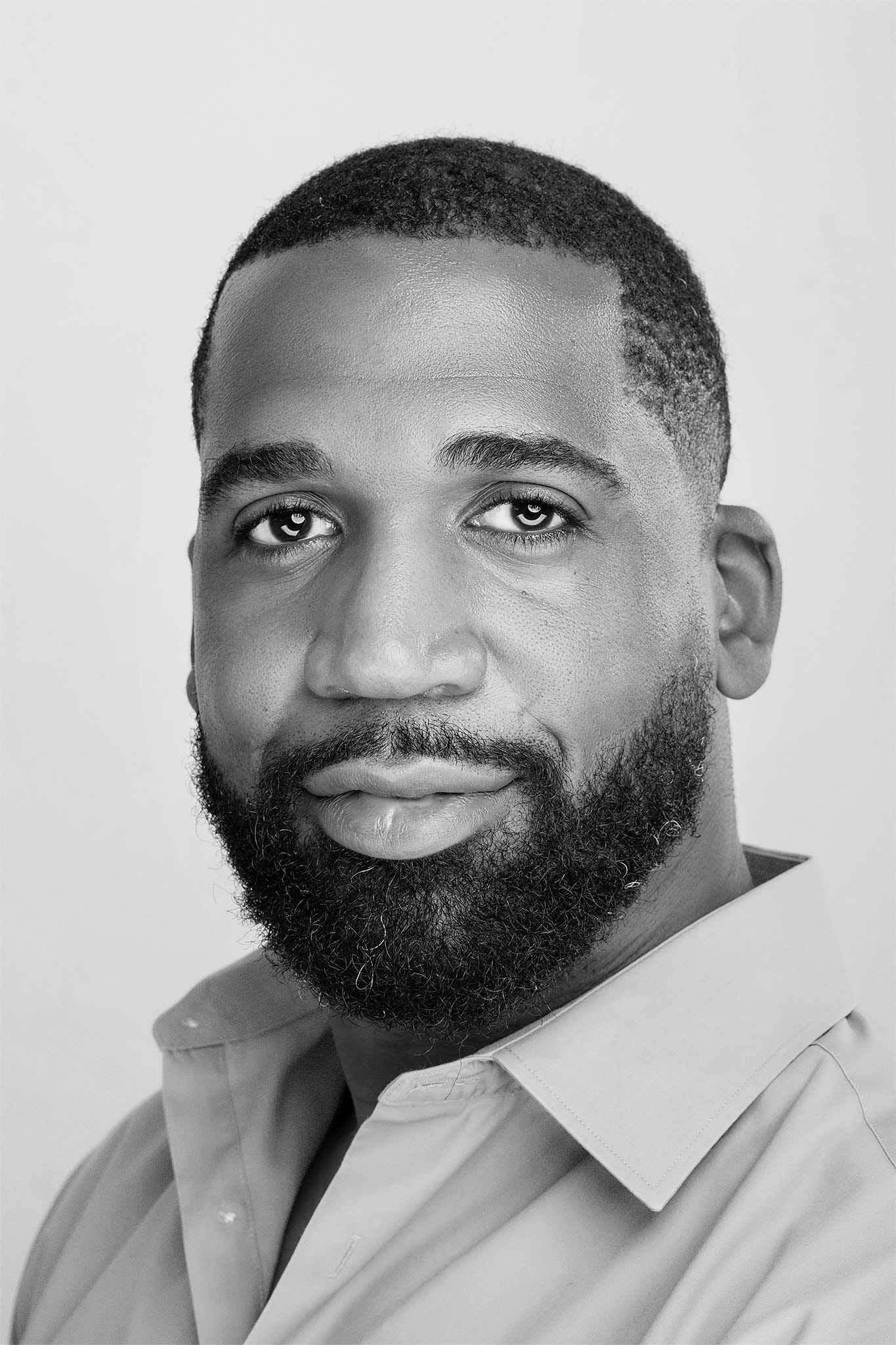 Black and white professional headshot of a man with a beard wearing a collared shirt.