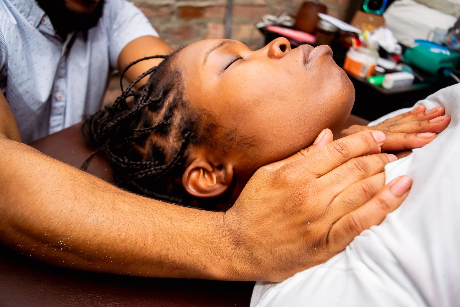 Massage therapist performing neck and shoulder massage on relaxed female client.