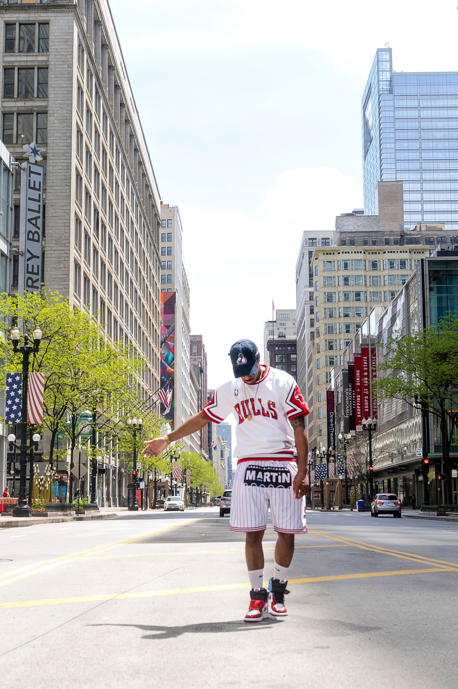 Man in Bulls jersey and Martin shorts poses on urban Chicago street.