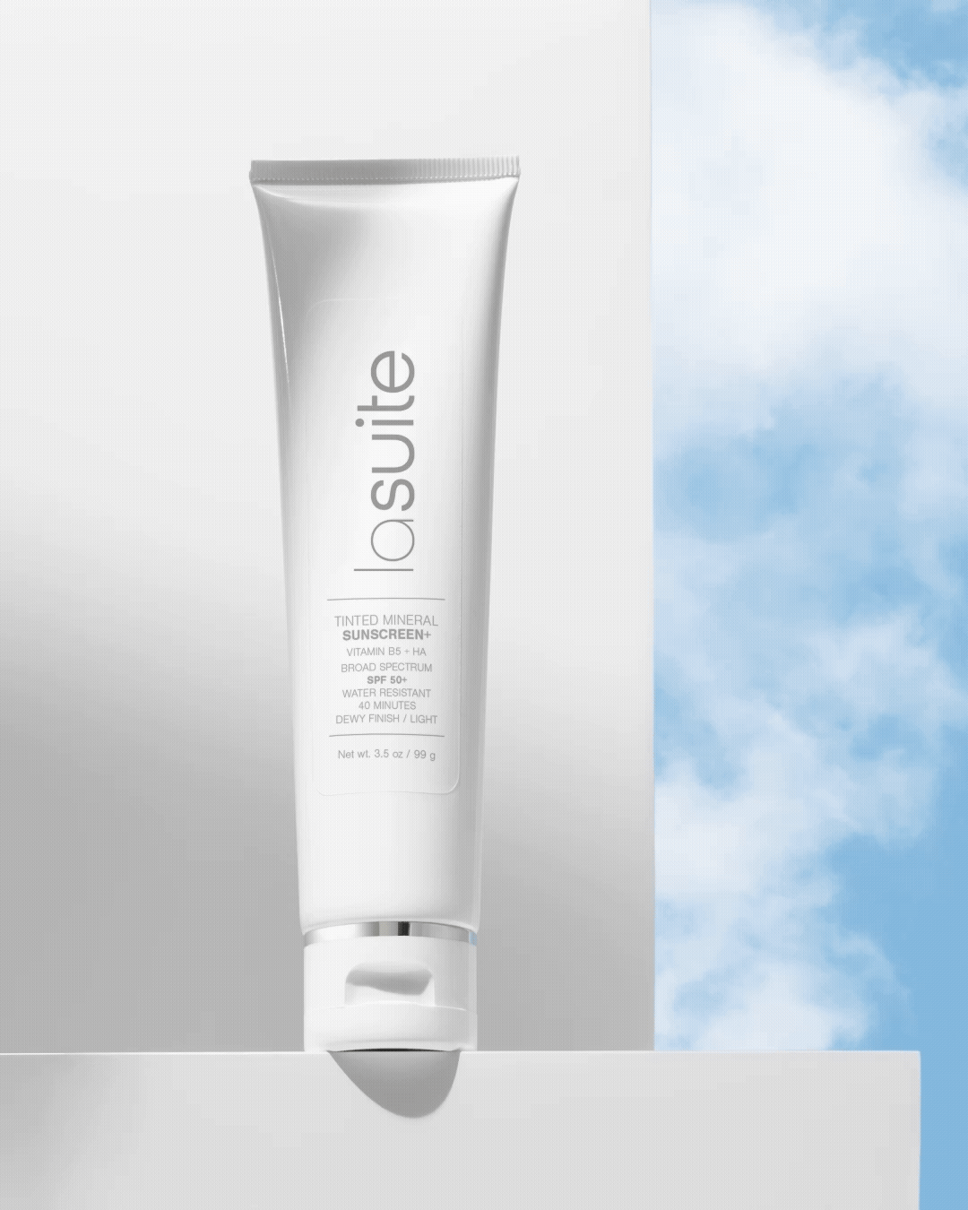 La Suite Skincare sunscreen tube on a white block with a bright sunlight and moving clouds in the background.