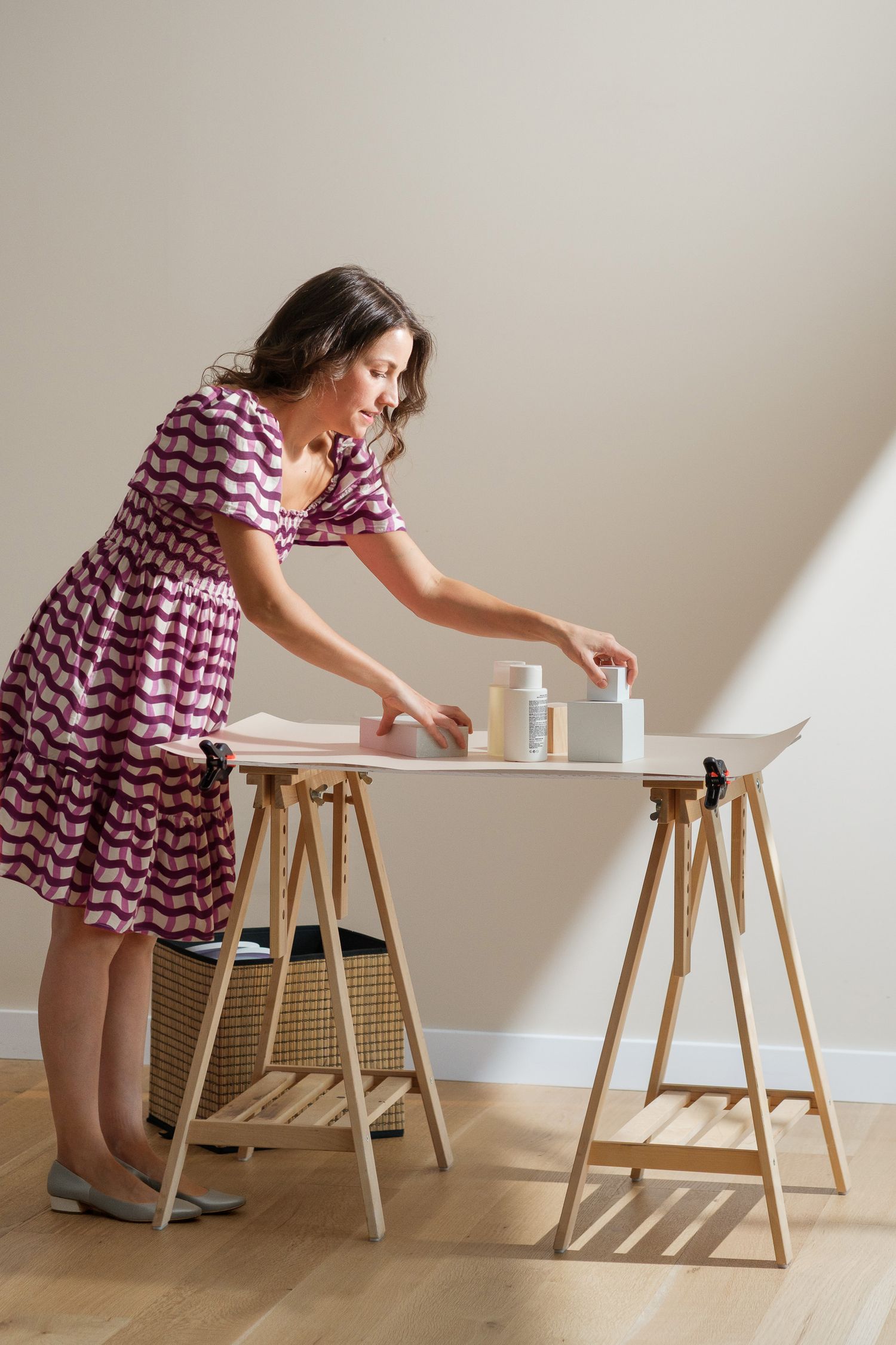 Darina arranging products and blocks in her home photography studio with bright sun light.