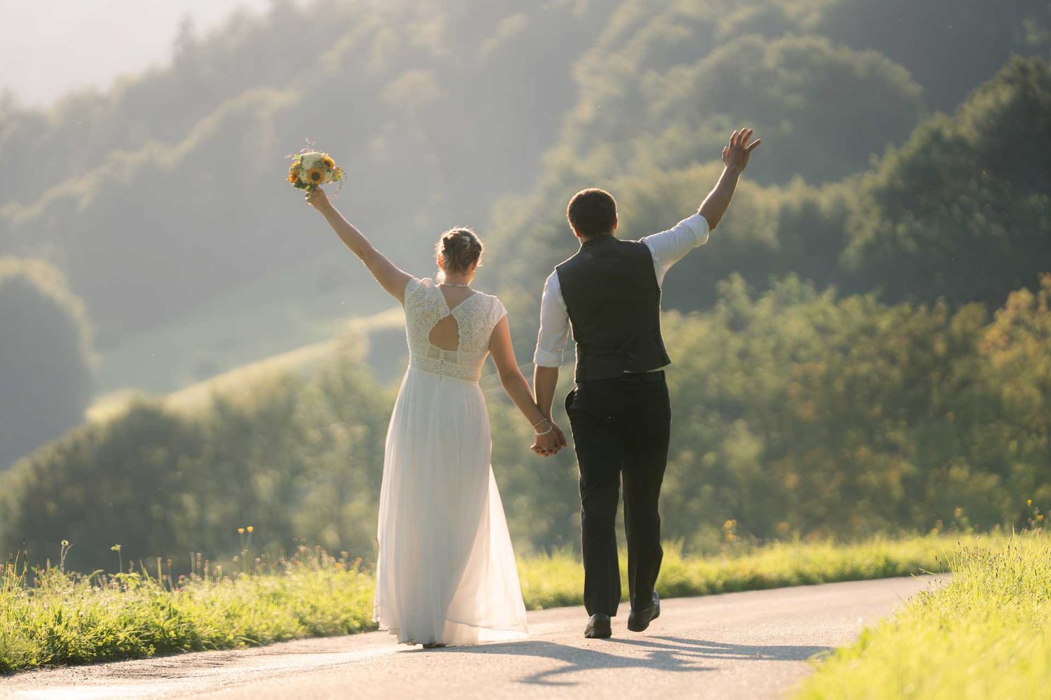 Hochzeitspaar auf einer Strasse verlässt die Hochzeit - Hand in Hand gehend.