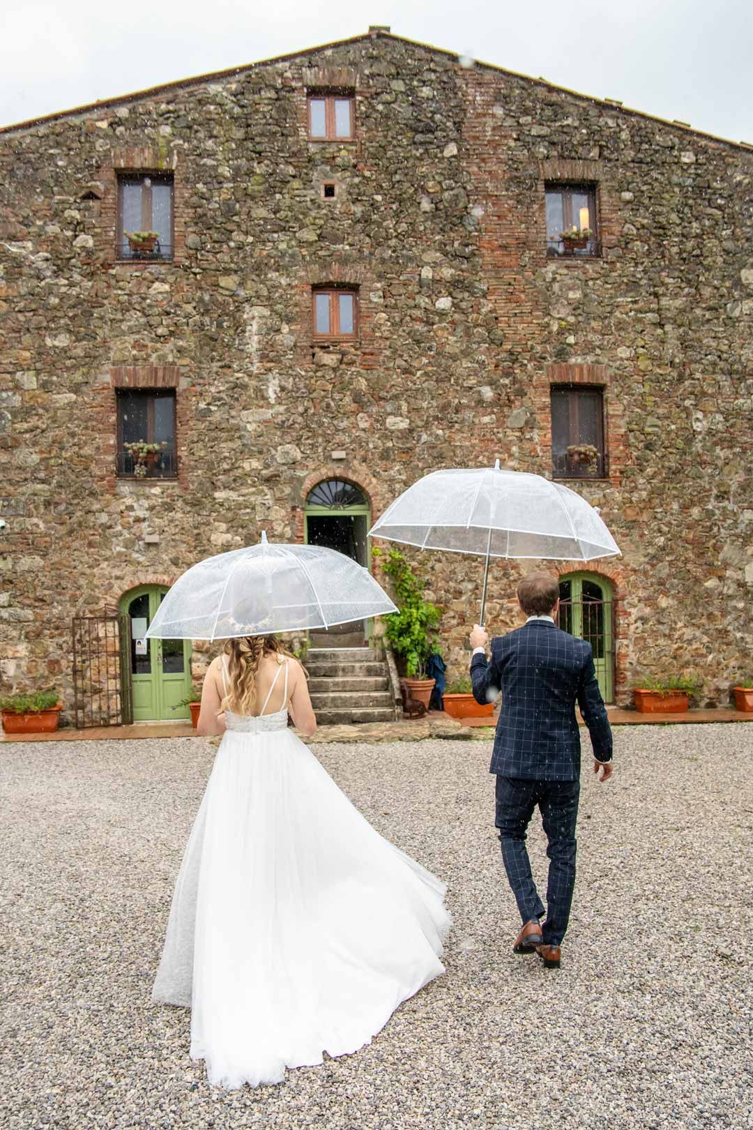 Hochzeitsfotografie: läuft mit Regenschirm auf ein Haus in der Toskana zu