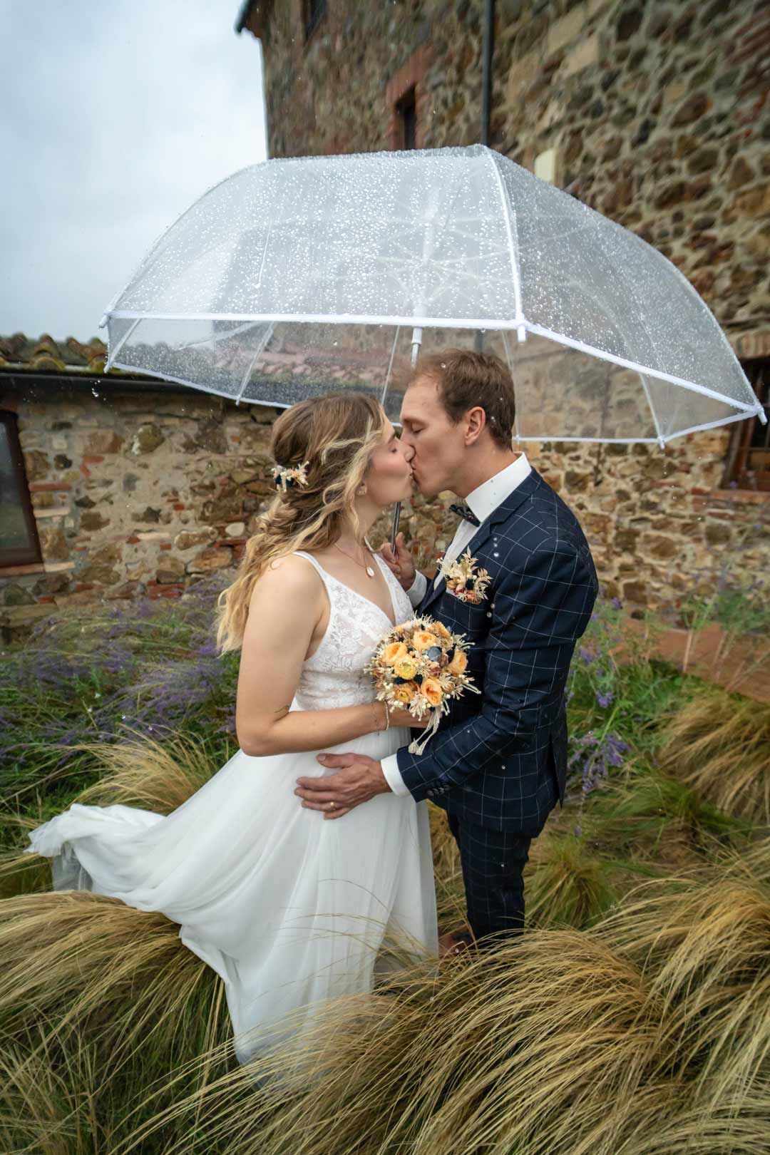 Hochzeitsfotografie: Paar küsst sich im Regen und einem Regenschirm