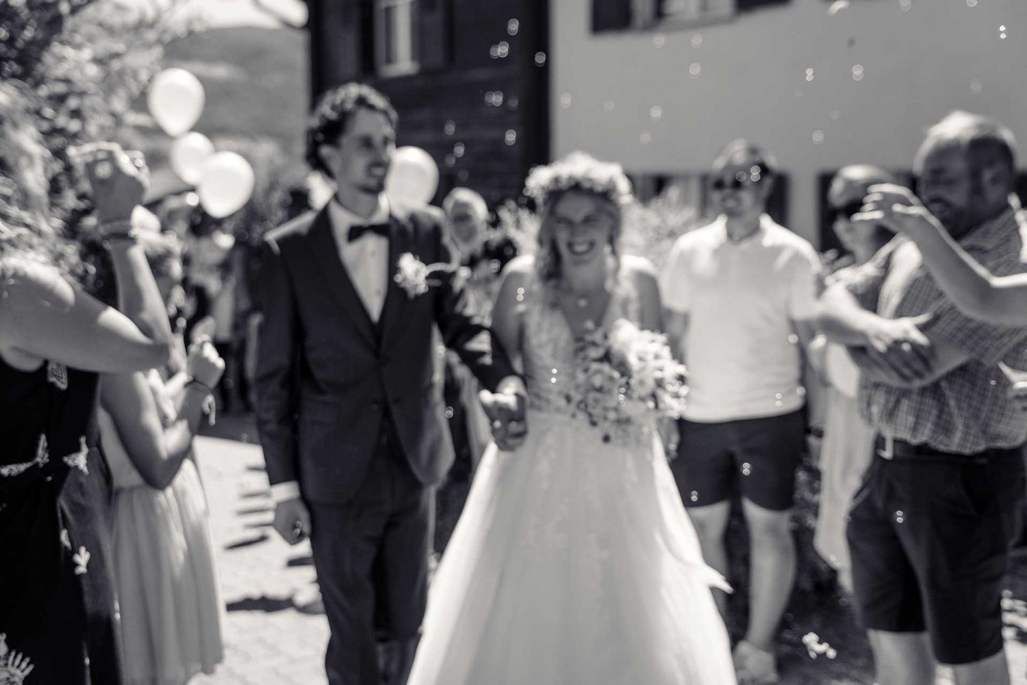 Hochzeitsfotografie: Hochzeitspaar läuft durch den Spalier – Fokus auf die Seifenblasen