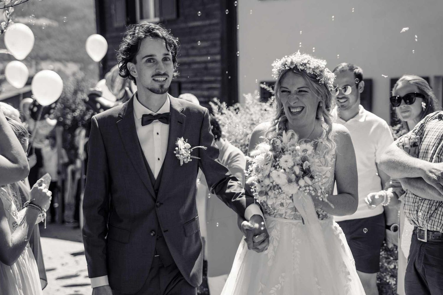 Hochzeitsfotografie: Hochzeitspaar läuft durch den Spalier der Gäste und geniessen den Moment nach der Trauung – Schwarzweissfotografie