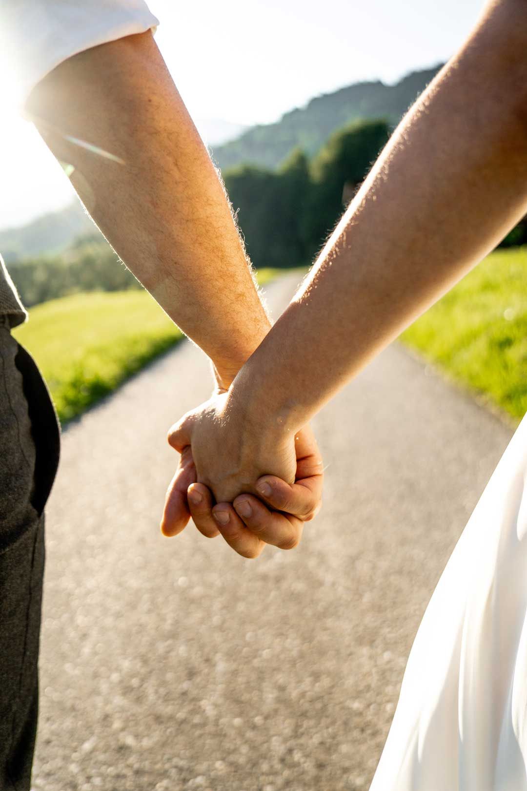 Hochzeitsfotografie: Das Hochzeitspaar läuft Hand in Hand der Sonne entgegen