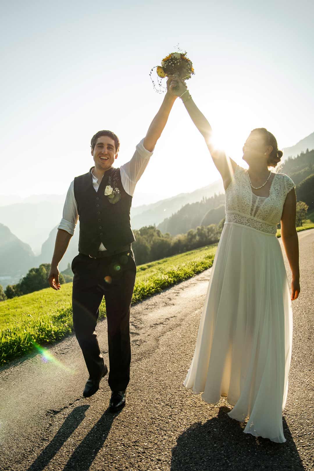 Hochzeitsfotografie: Hochzeitspaar streckt zusammen den Hochzeitsstrauss in die Luft