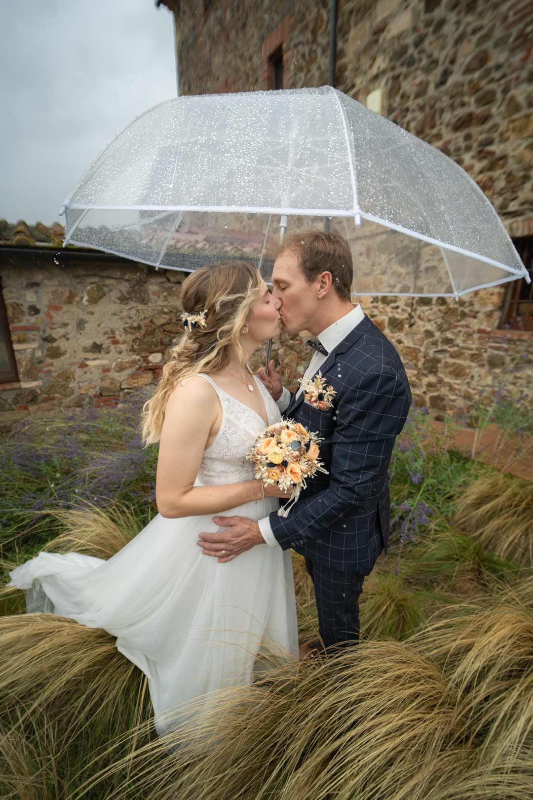 Hochzeitsfotografie: Paar küsst sich im Regen und einem Regenschirm