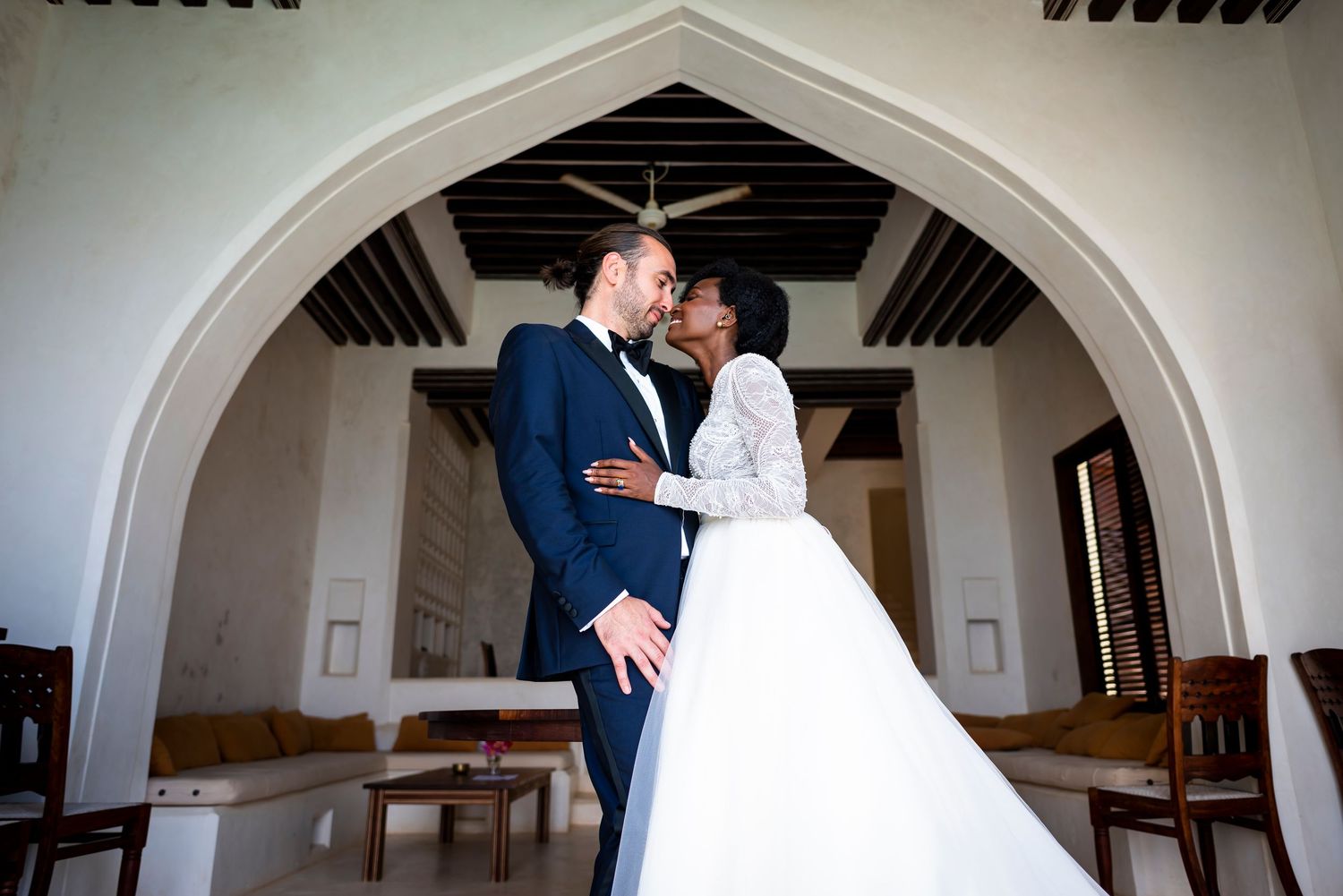 A romantic wedding couple shares an intimate moment under an elegant arched doorway in a church.