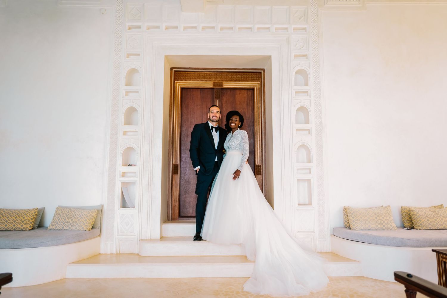 A series of wedding photos showing a couple in formal attire walking through elegant white doorways and archways.