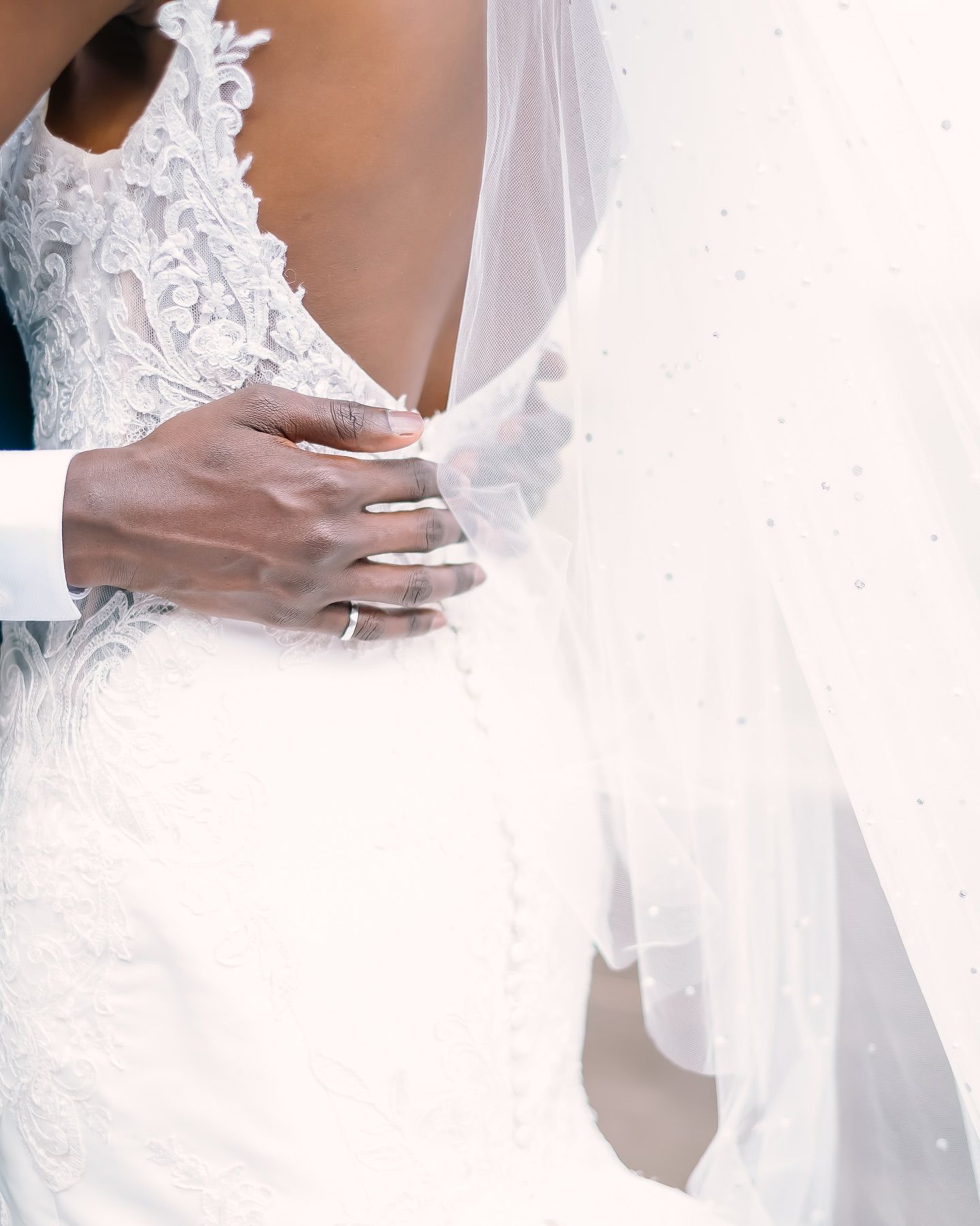 Close-up details of a white lace wedding dress with delicate beading and embroidery patterns.