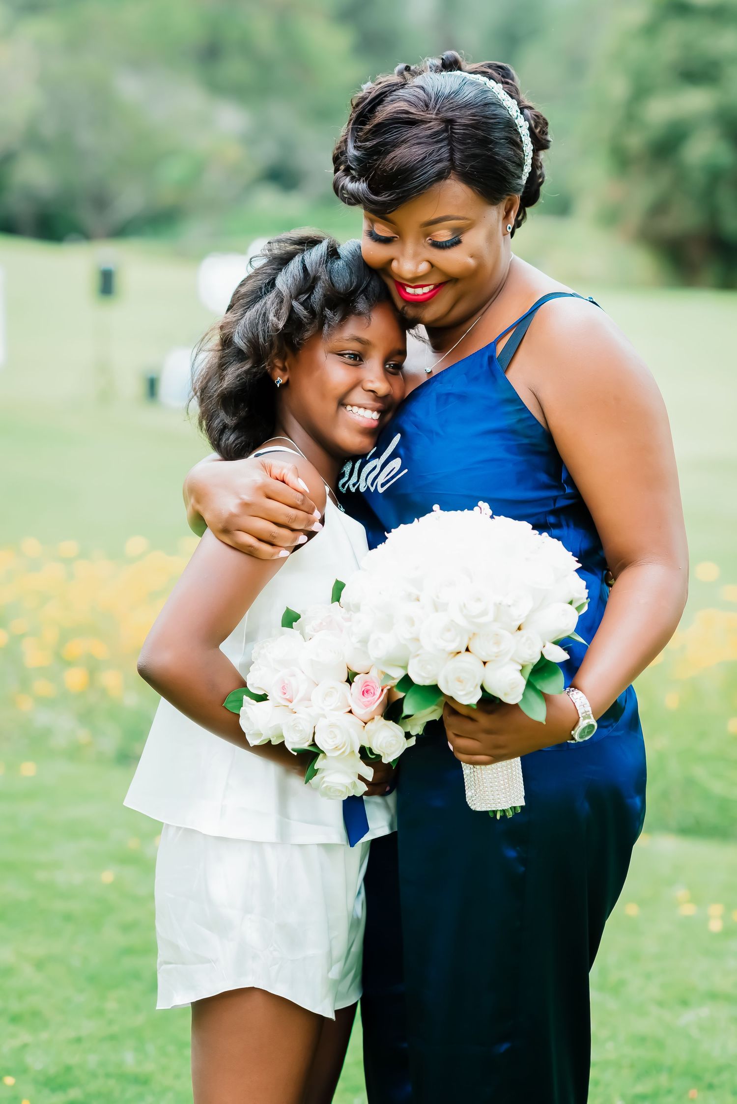 Two people embrace while holding a beautiful bouquet of white peonies in an outdoor garden setting.