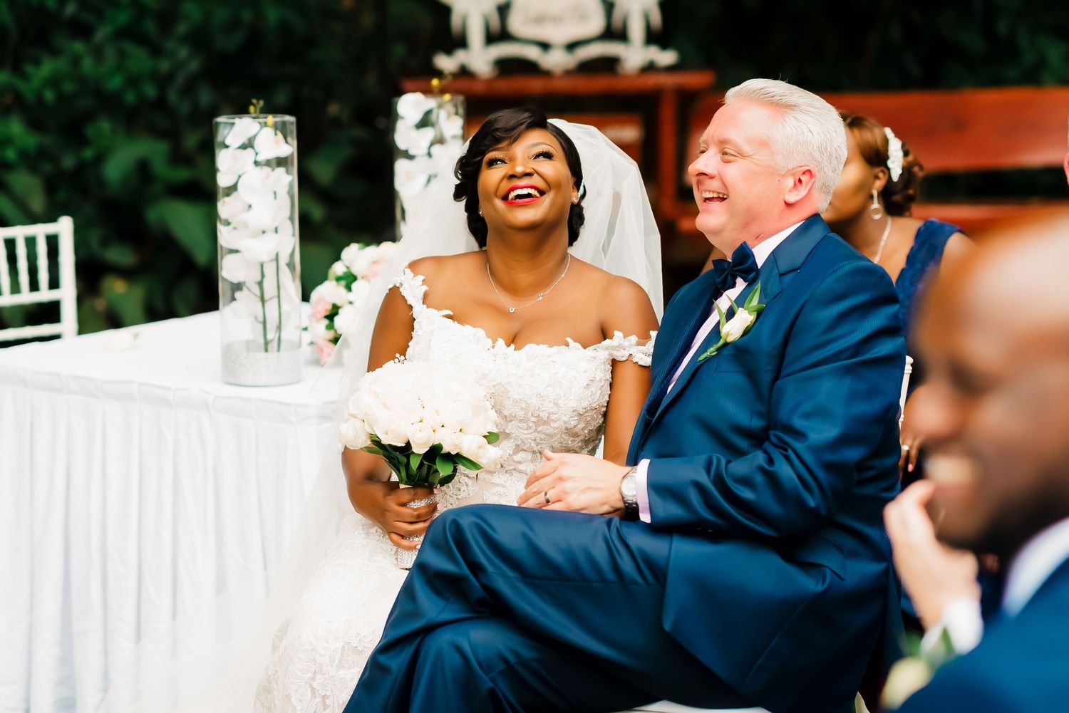 A happy couple laughs together during their wedding reception at an elegant indoor venue.