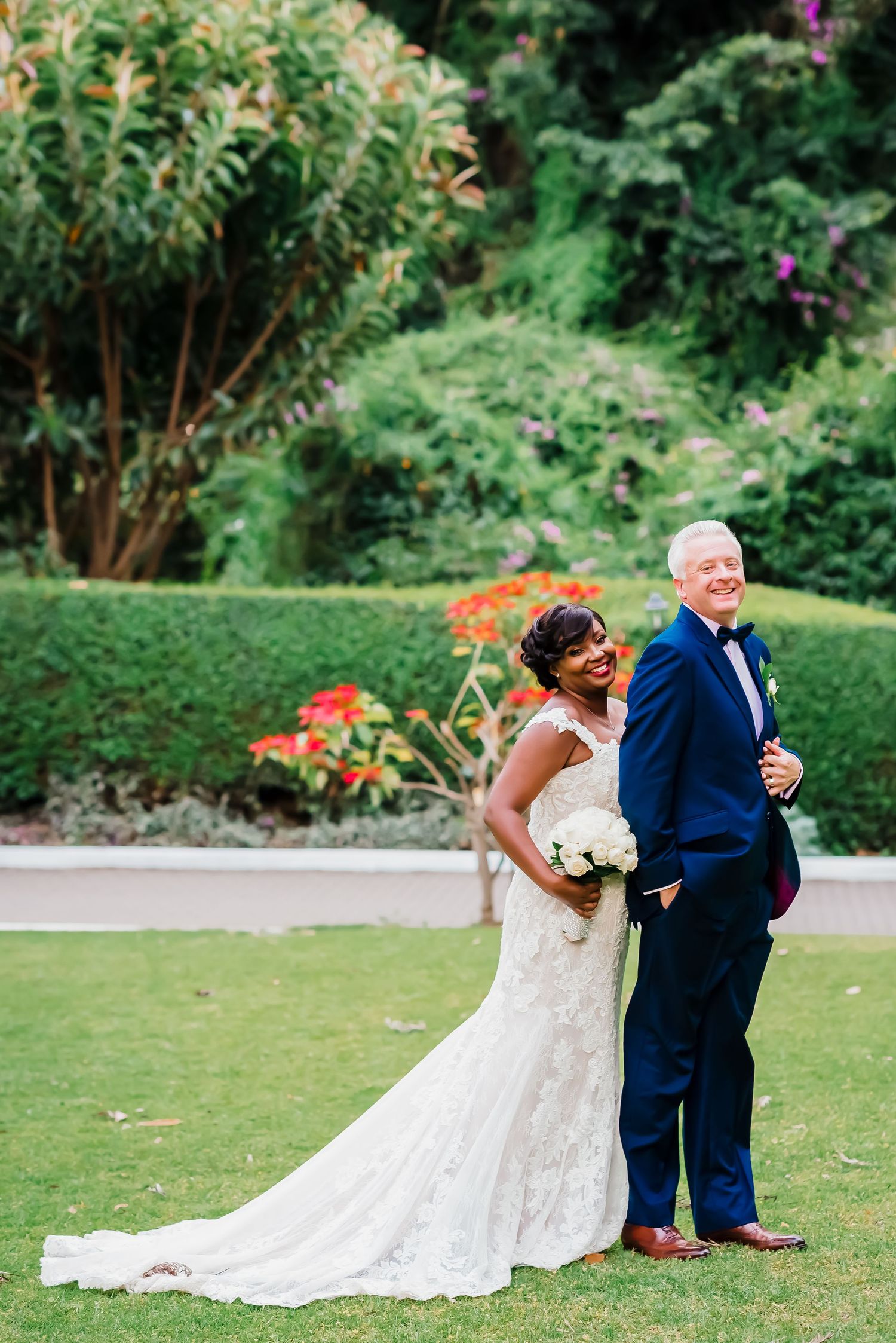 A couple shares a first look moment in their wedding attire on a lush green lawn.