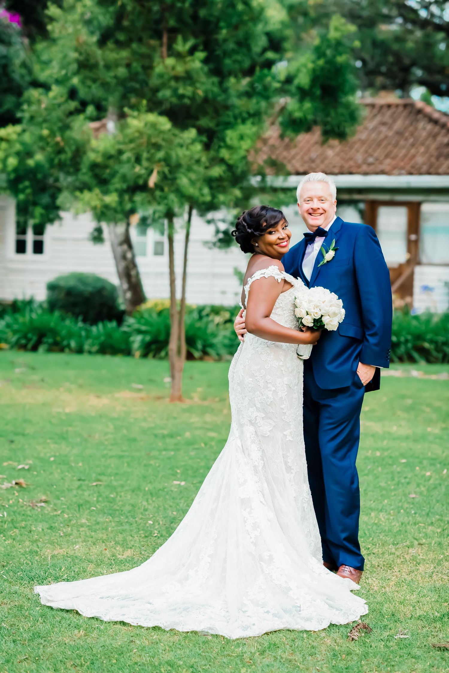A romantic wedding photo series showing a couple in formal attire embracing outdoors on a grassy lawn with trees.