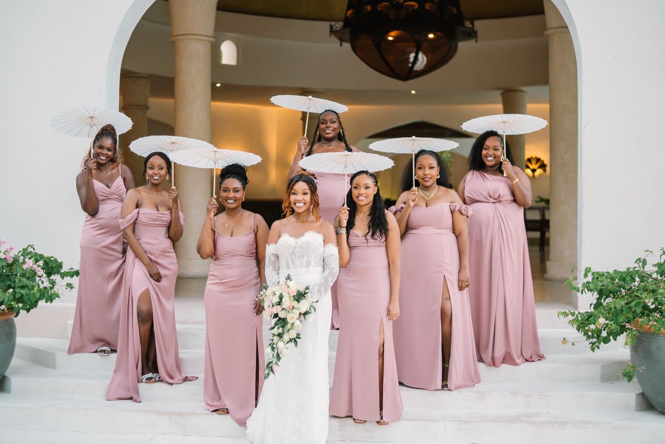 Bridesmaids in matching pink dresses pose together during a wedding celebration at an elegant venue.