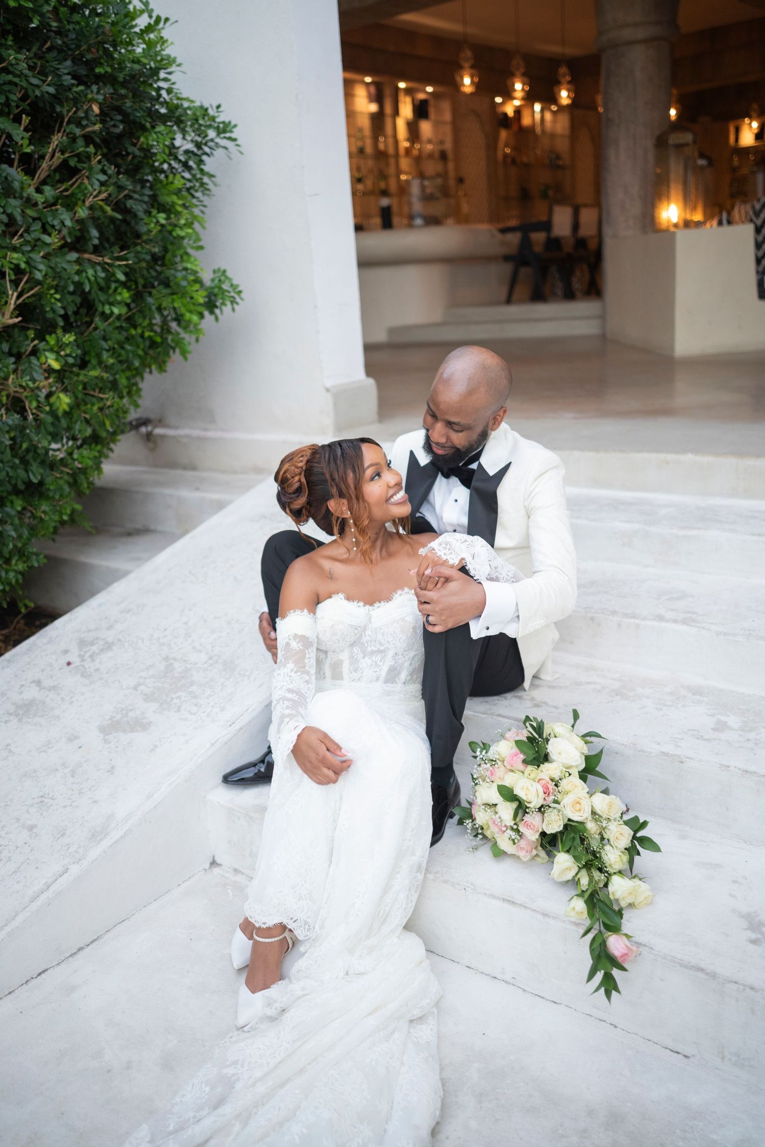 A romantic wedding couple shares intimate dance poses on white marble steps during their special day celebration.