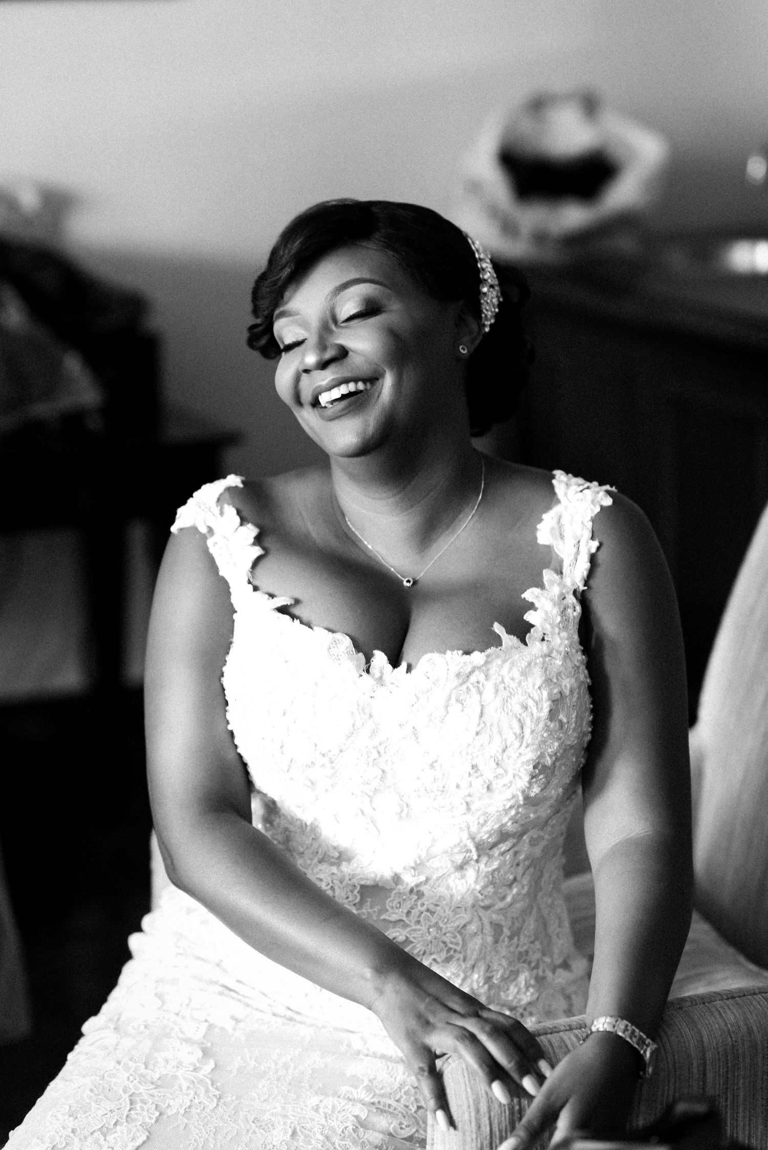 A radiant bride in a white lace wedding dress smiles joyfully in this black and white portrait.