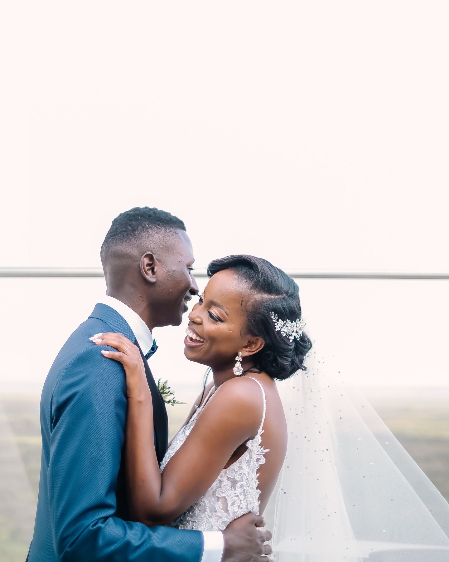 A joyful couple shares an intimate moment during their wedding photoshoot outdoors.