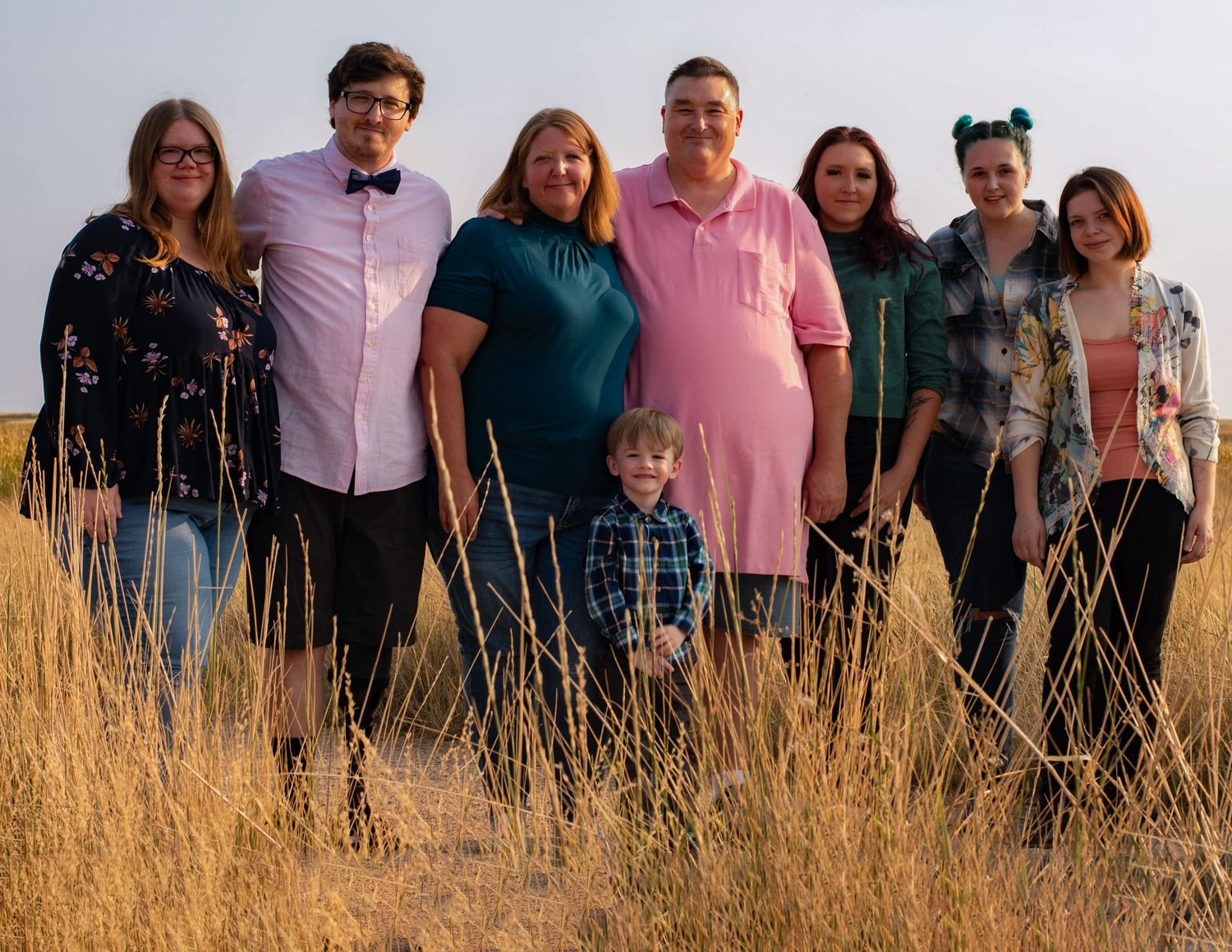 A group stands together in a field of tall golden grass at sunset.