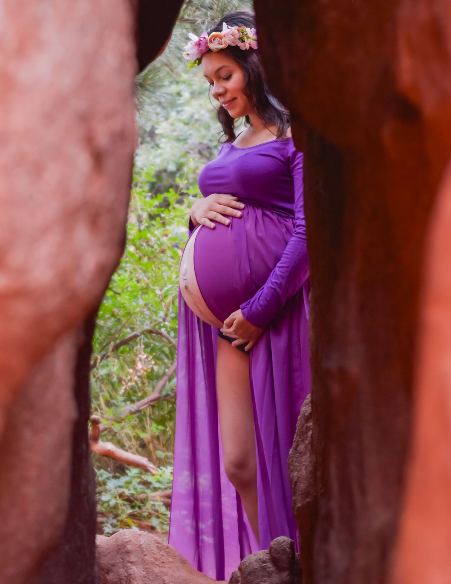 A romantic maternity photoshoot in a purple dress against a rustic backdrop.