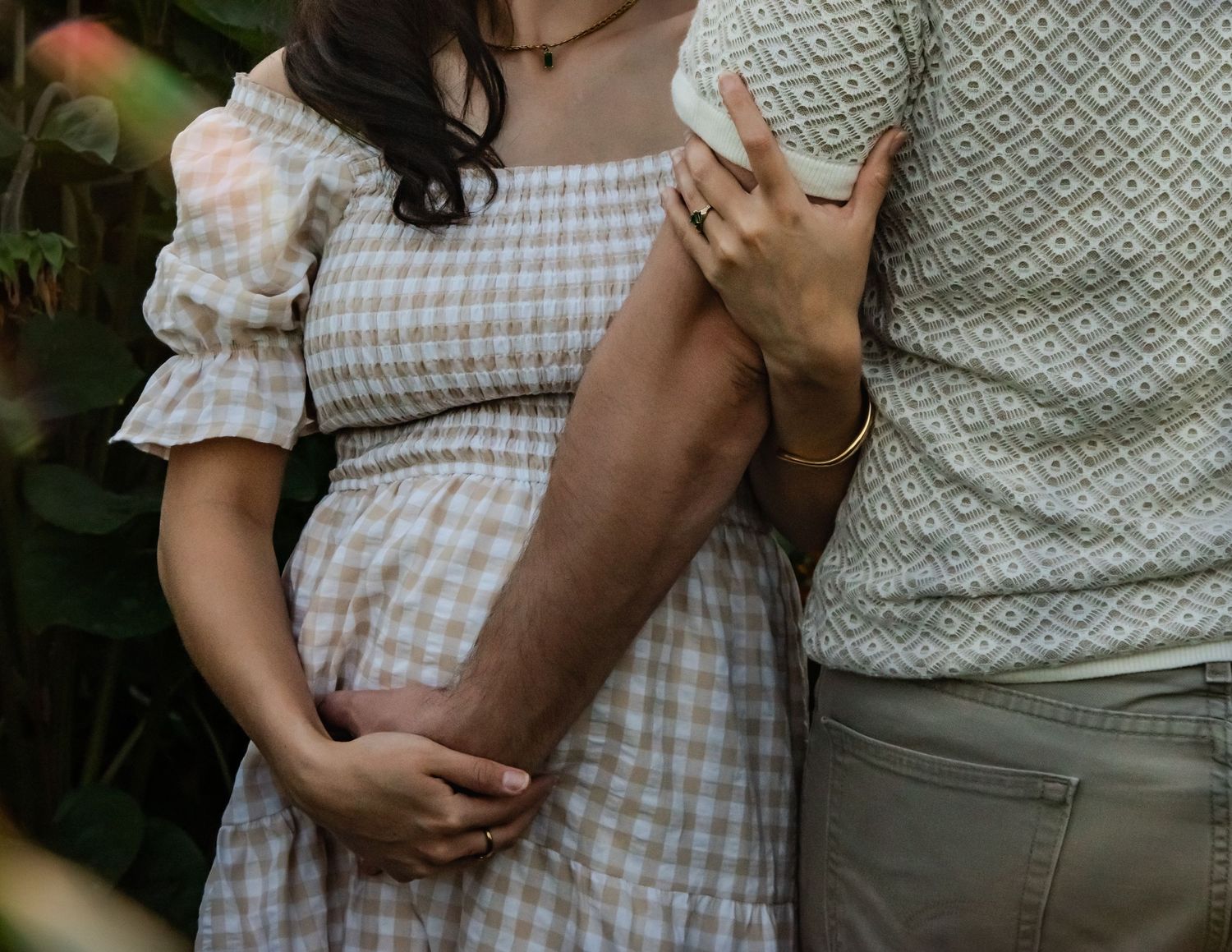 Intimate maternity photos featuring a gingham dress and casual outdoor styling.